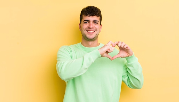 sorridendo e sentendosi felice carino romantico e innamorato a forma di cuore con entrambe le mani