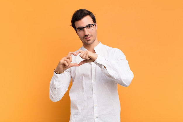 sorridendo e sentendosi felice, carino, romantico e innamorato, facendo a forma di cuore con entrambe le mani