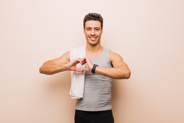 sorridendo e sentendosi felice, carino, romantico e innamorato, facendo a forma di cuore con entrambe le mani