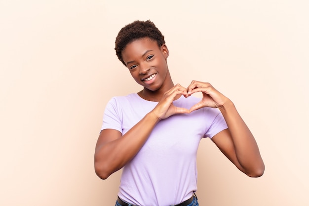 sorridendo e sentendosi felice, carino, romantico e innamorato, facendo a forma di cuore con entrambe le mani