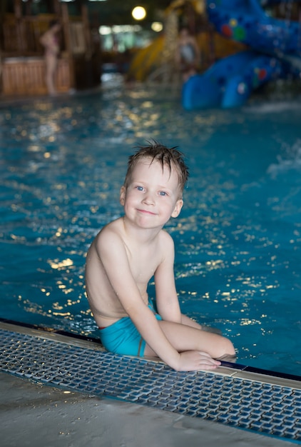 Sorridendo felice ragazzo seduto in piscina