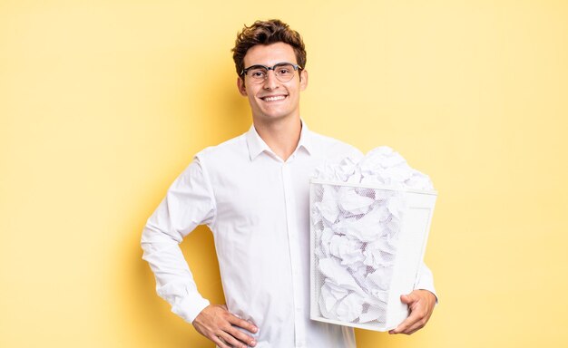 Sorridendo felicemente con una mano sull'anca e fiducioso positivo atteggiamento orgoglioso e amichevole concetto di carta spazzatura