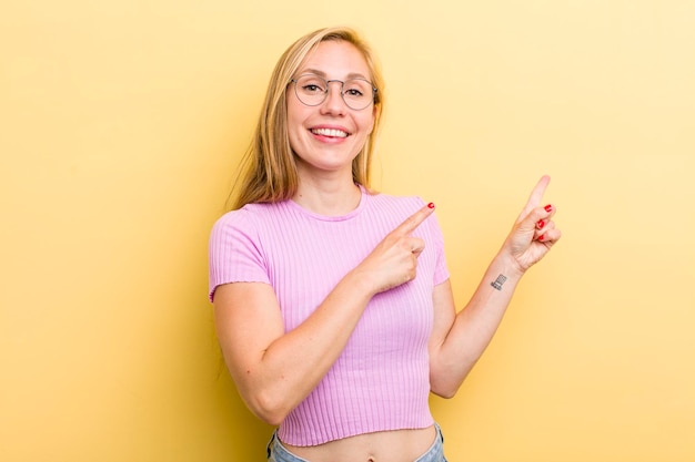 Sorridendo felicemente e indicando il lato e verso l'alto con entrambe le mani che mostrano l'oggetto nello spazio della copia