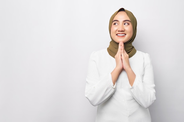 Sorridente amichevole giovane donna musulmana asiatica di 20 anni che indossa l'hijab gesticolando Eid Mubarak salutando e guardando lo spazio vuoto isolato su sfondo bianco Persone concetto di stile di vita religioso