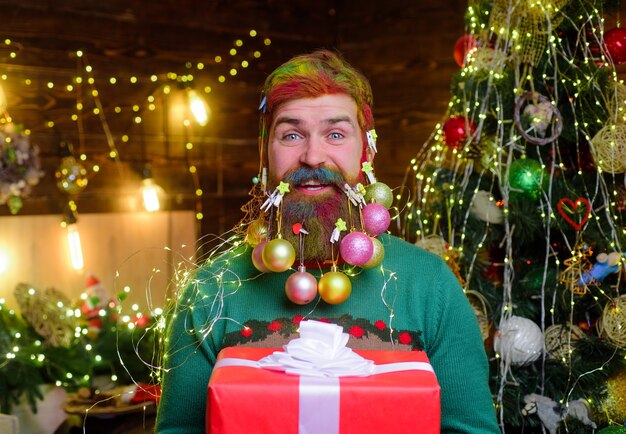 Sorridente babbo natale con regalo di natale vacanze capodanno uomo barbuto con barba decorata hold
