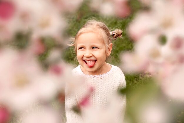 Sorridente bambina fotografata attraverso i rami fioriti di un albero