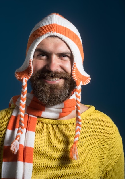 Sorridente bell'uomo barbuto che indossa un cappello e una sciarpa divertenti invernali uomo attraente con barba e