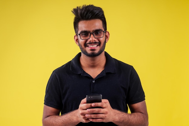 Sorridente bell'uomo indiano che fotografa selfie in studio su sfondo giallo.