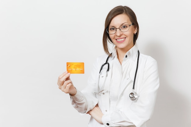 Sorridente bella donna medico con stetoscopio isolato su sfondo bianco. Medico femminile in abito medico che mostra carta di credito in bianco di affari. Personale sanitario, salute, finanza, concetto di medicina.