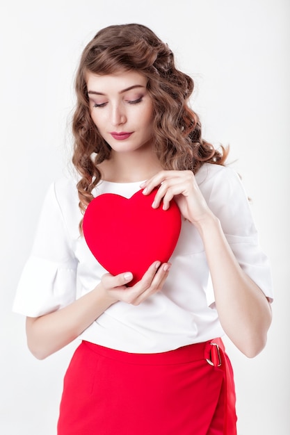 Sorridente bella donna riccia con palloncini d'aria a forma di cuore per il giorno di San Valentino