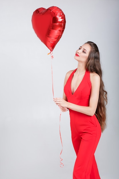 Sorridente bella donna riccia con palloncini d'aria a forma di cuore per il giorno di San Valentino