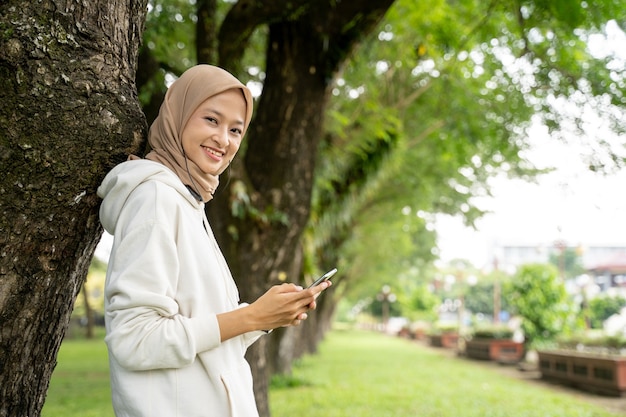 Sorridente bella giovane donna musulmana utilizzando il telefono cellulare durante la pausa esercizio all'aperto