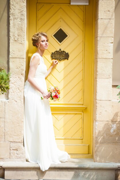 Sorridente bella sposa il giorno del matrimonio con un grande bouquet vicino alla chiesa.