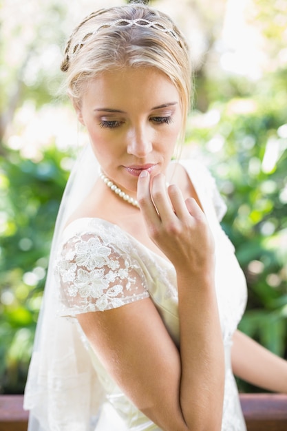 Sorridente bionda sposa in collana di perle che tocca le sue labbra