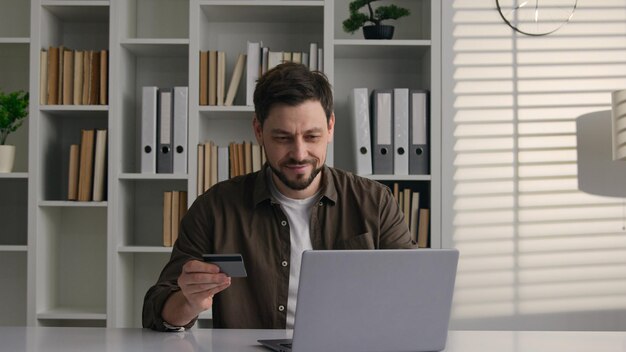 Sorridente cliente maschio soddisfatto uomo caucasico uomo d'affari lavoratore a casa ufficio usare laptop pagare denaro