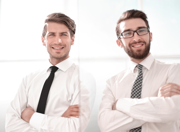 Sorridente colleghi di lavoro in piedi in un luminoso concetto di officebusiness