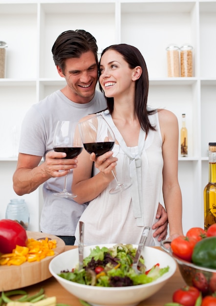 Sorridente coppia bere vino e preparare un'insalata