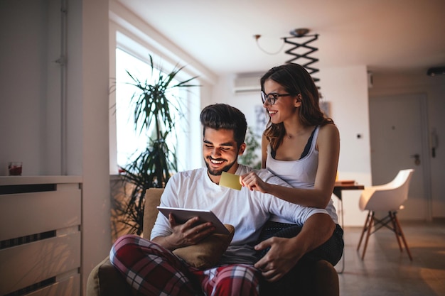 Sorridente coppia giovane shopping online su tavoletta digitale a casa