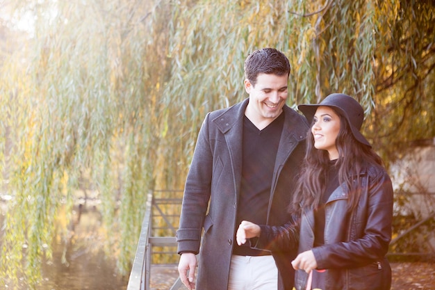 Sorridente coppia gourgeous felice che cammina nel parco d'autunno vicino a un lago