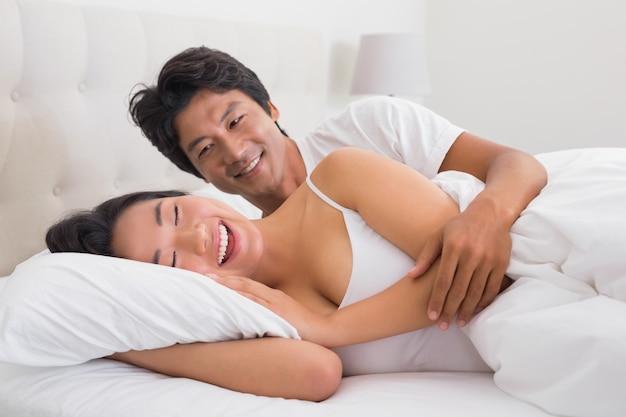 Sorridente coppia sdraiata a letto