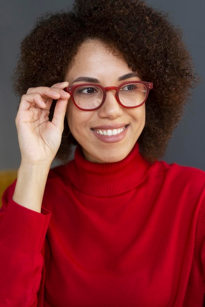 Sorridente donna afroamericana che indossa eleganti occhiali rossi e dolcevita rosso che guarda lontano