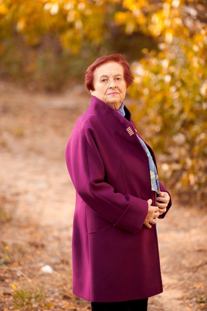 Sorridente donna anziana che indossa elegante cappotto invernale in posa nel parco