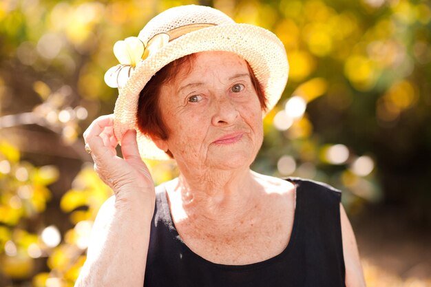 Sorridente donna anziana che indossa un cappello all'aperto