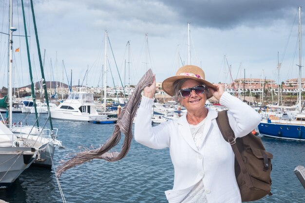 Sorridente donna anziana che si gode un'escursione in mare al porto in una ventosa giornata estiva