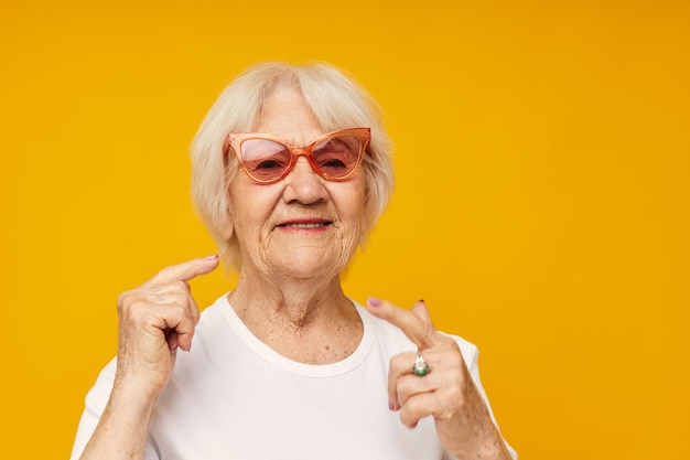 Sorridente donna anziana in una maglietta bianca indossa occhiali sfondo isolato