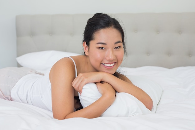 Sorridente donna asiatica sdraiata sul letto