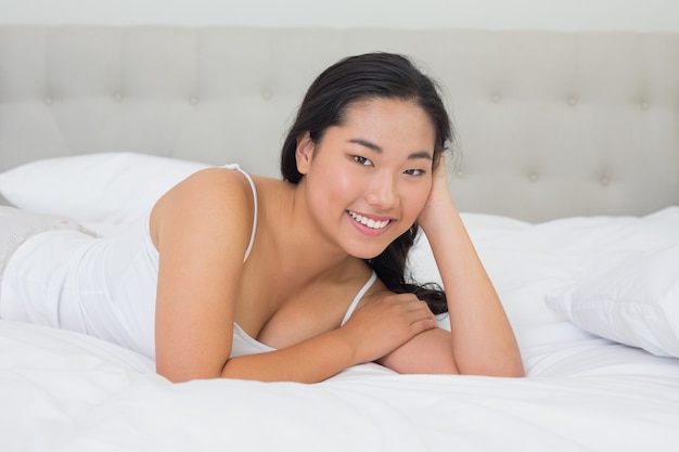 Sorridente donna asiatica sdraiata sul letto