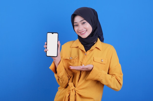 Sorridente donna asiatica tenendo il telefono cellulare sul blu