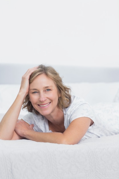 Sorridente donna bionda sdraiata sul letto