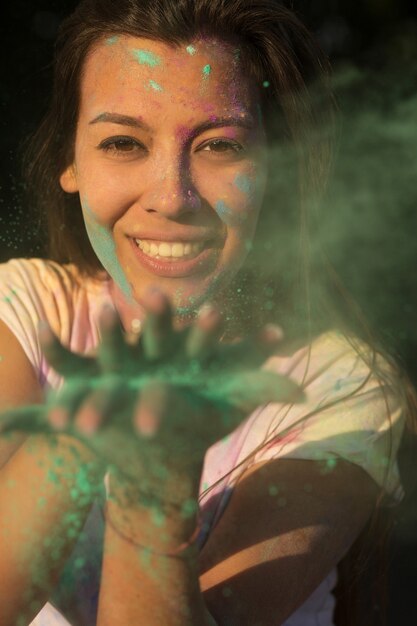 Sorridente donna bruna abbronzata che si diverte con la vernice secca Holi verde