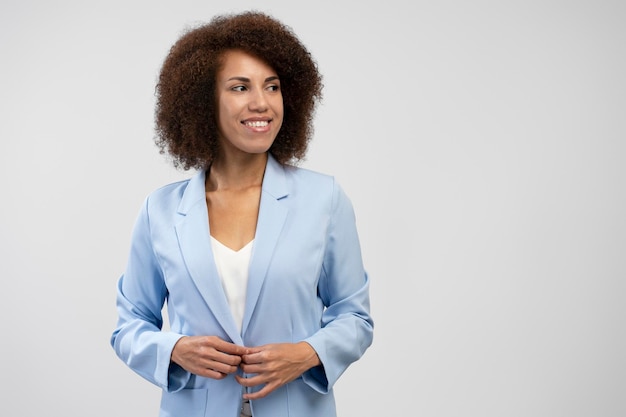 Sorridente donna d'affari afroamericana che indossa un abito elegante distogliendo lo sguardo isolato sullo sfondo