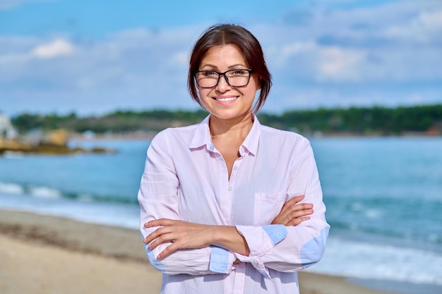 Sorridente donna di mezza età con le mani piegate che guarda l'obbiettivo