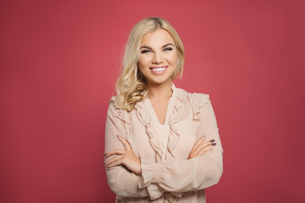 Sorridente donna di successo su sfondo rosa colorato Ragazza bionda con le braccia incrociate e bel sorriso