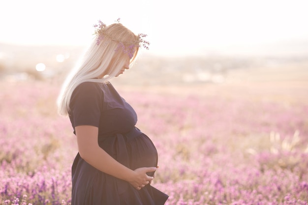 Sorridente donna incinta in un prato di fiori di lavanda