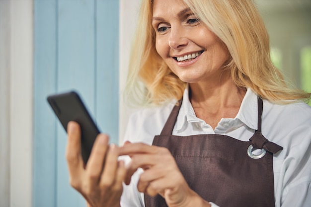 Sorridente donna matura che fissa il suo gadget