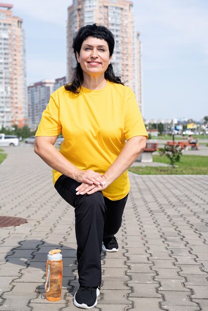 Sorridente donna senior che si estende all'aperto nel parco