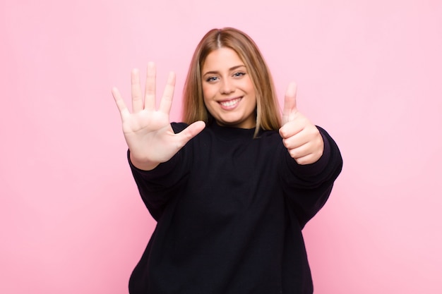 sorridente e amichevole, mostrando il numero sei o il sesto con la mano in avanti, il conto alla rovescia