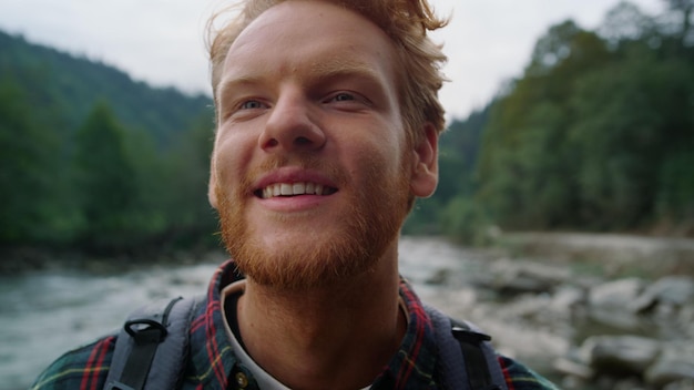 Sorridente escursionista in piedi nel paesaggio di montagna Ritratto di uomo redhead guardando la fotocamera all'aperto Closeup ridendo ragazzo in posa a porte chiuse Emozione maschio faccia felice