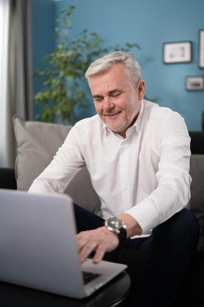 Sorridente felice uomo anziano di mezza età che utilizza la tecnologia del computer portatile che lavora navigando online