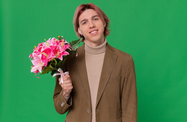 Sorridente giovane bell'uomo con in mano un mazzo di fiori e guardando