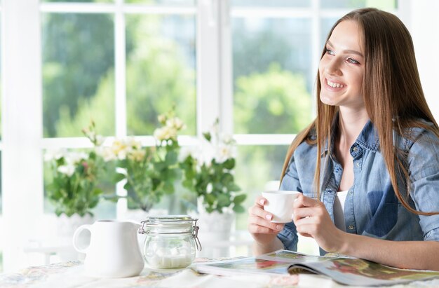 Sorridente giovane bella donna con rivista in cucina