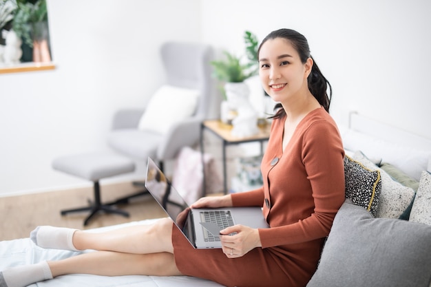 Sorridente giovane donna asiatica che utilizza un computer portatile nel suo negozio