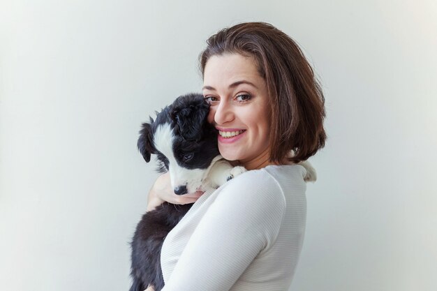 Sorridente giovane donna attraente che abbraccia abbracciando simpatico cucciolo di cane border collie isolato su sfondo bianco...