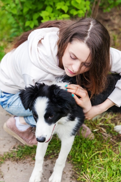 Sorridente giovane donna attraente che abbraccia huging carino cucciolo di cane border collie in estate parco cittadino sfondo all'aperto