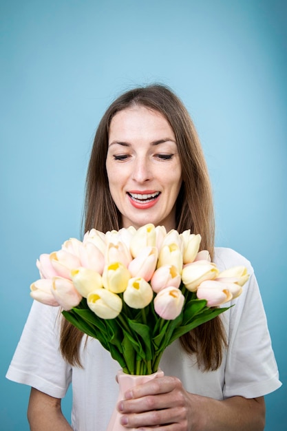 Sorridente giovane donna azienda bouquet di tulipani su sfondo blu