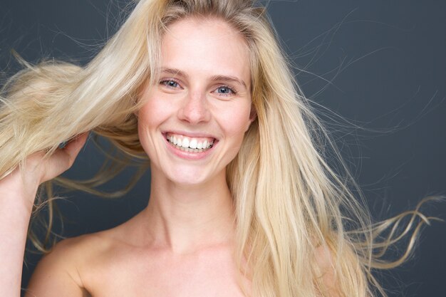 sorridente giovane donna bionda con i capelli che soffia